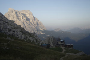 Rifugio Coldai in the foreground with Monte Pelmo in Golden sunlight in the distance