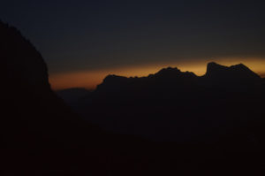 The peaks in the distance illuminated by the orange glow of sunset