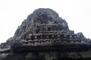 A large face above intricate carvings at the Bayon temple